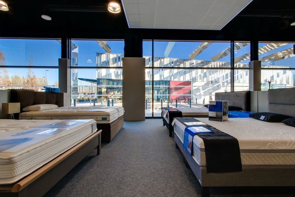 Photo de la vitrine du magasin vue de l'intérieure présentant la gamme de matelas proposée par Vitaliterie