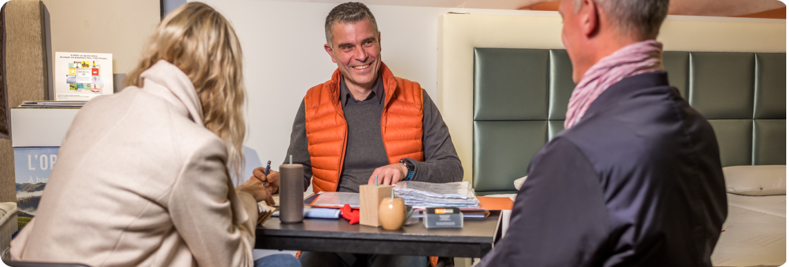 Photo de Timothée, gérant du magasin Vitaliterie, conseillant 2 clients vus de dos dans l'achat de leur nouvelle literie